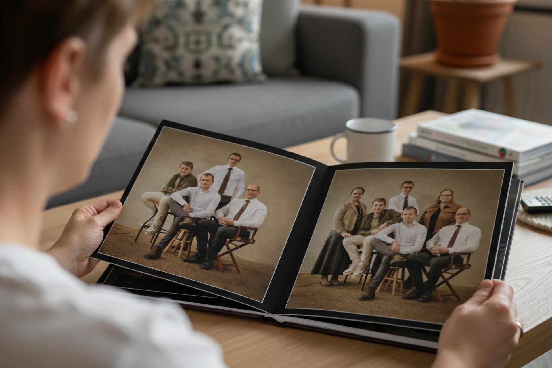 Bovenaanzicht van een vierkant bruin leren fotoboek op een houten koffietafel, met een venster op de cover waarin witte bloemen en de tekst '25 jaar getrouwd' te zien zijn.